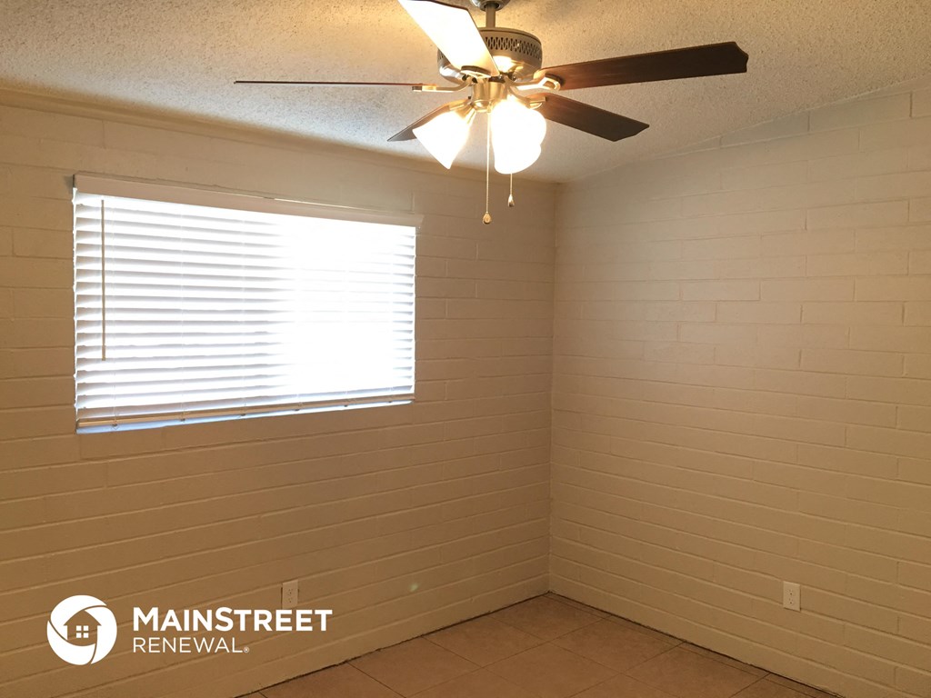 a small room with a ceiling fan and a window
