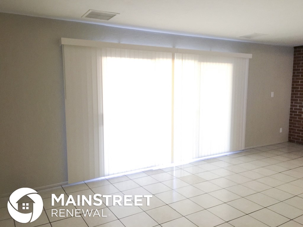 an empty living room with sliding glass doors and a tile floor