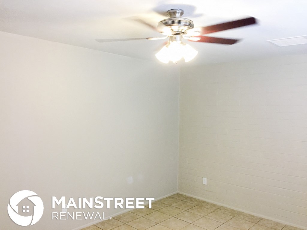 an empty room with a ceiling fan and a white brick wall