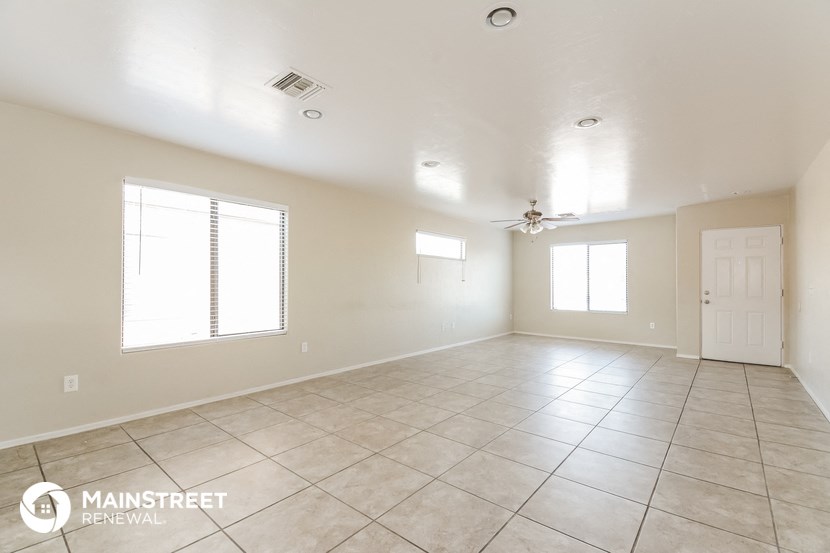 an empty living room with a ceiling fan and tile floor