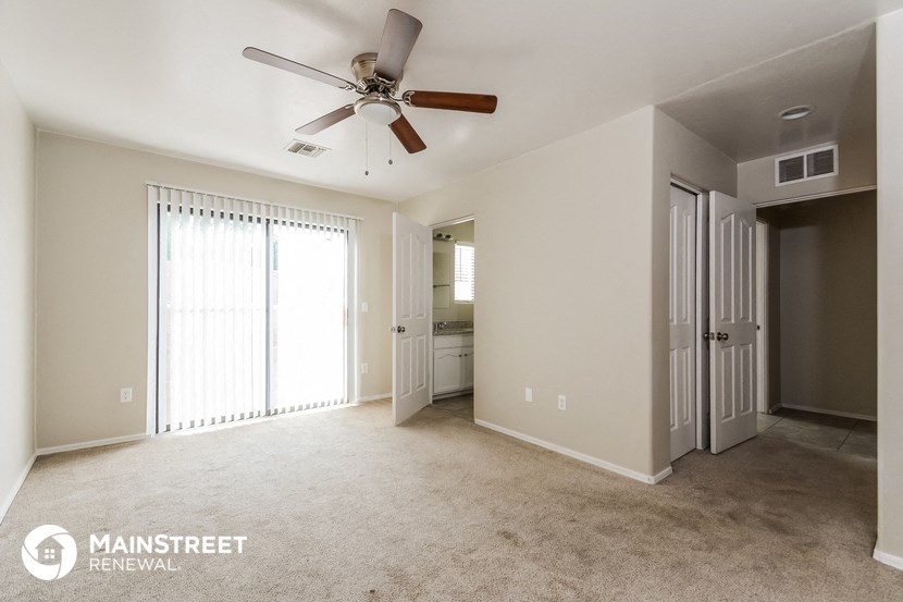 an empty living room with a ceiling fan and a closet