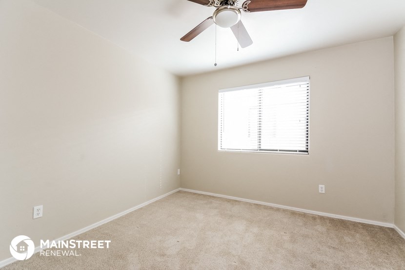a bedroom with a ceiling fan and a window