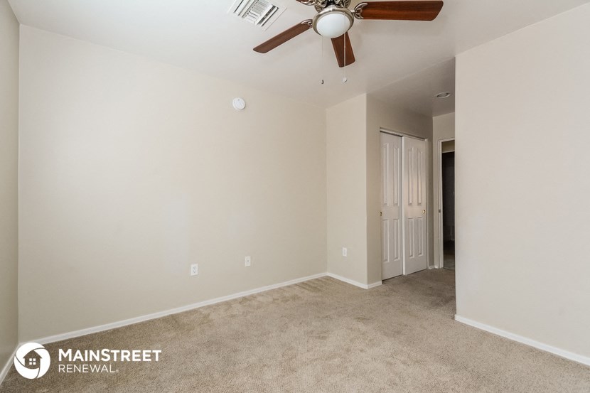a living room with a ceiling fan and a door to a hallway