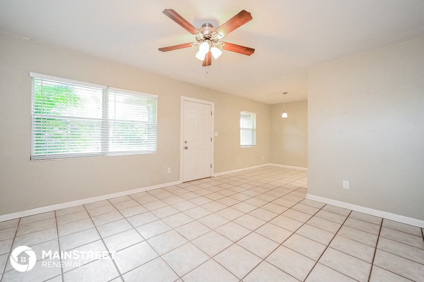 an empty living room with a ceiling fan and tiled floor