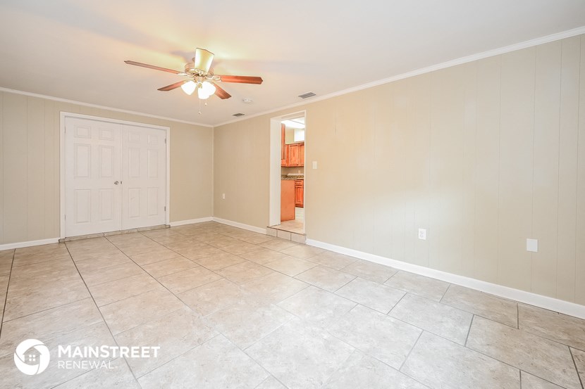a empty living room with tile flooring and a ceiling fan