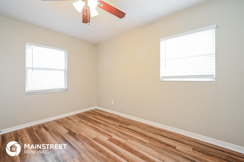the bedroom with wood flooring and two windows