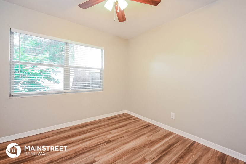 the bedroom has a large window and wood flooring