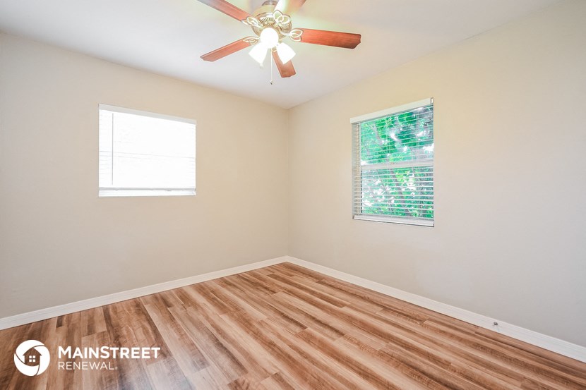 the living room with wood floors and a ceiling fan