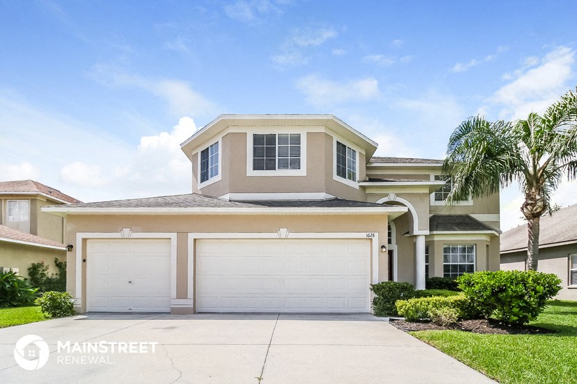 a beige house with a garage and a palm tree