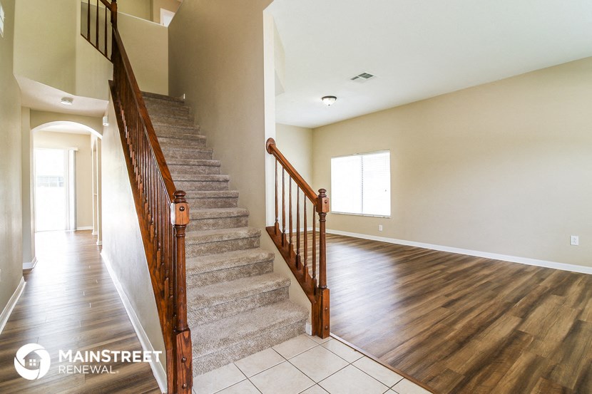 a staircase in a home with hardwood flooring and a hallway with stairs