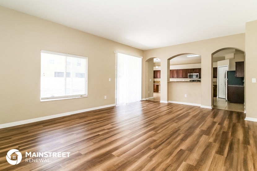 the living room and kitchen of an apartment with wood flooring