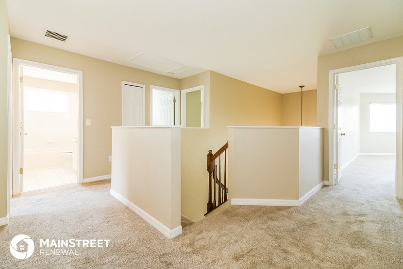 an empty living room and hallway with a staircase and a white partition wall