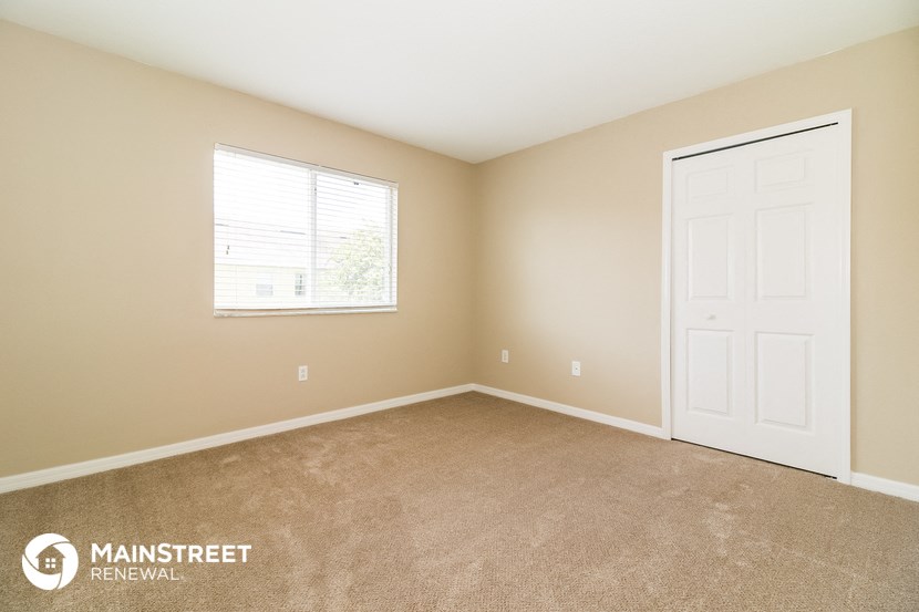 the upstairs bedroom has a carpeted floor and a white door and window