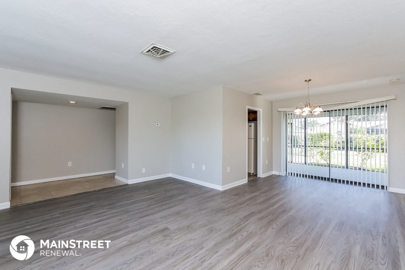 an empty living room with wood flooring and a large window