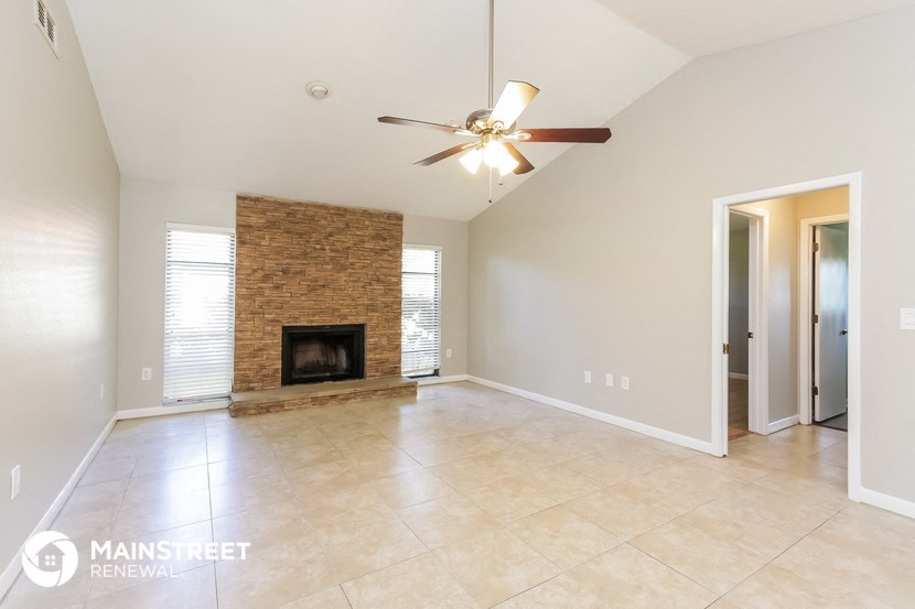 an empty living room with a fireplace and a ceiling fan