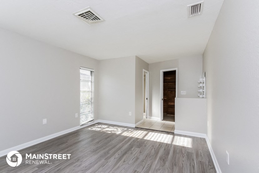 a spacious living room with white walls and wood flooring