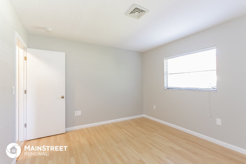 the living room with wood flooring and a window