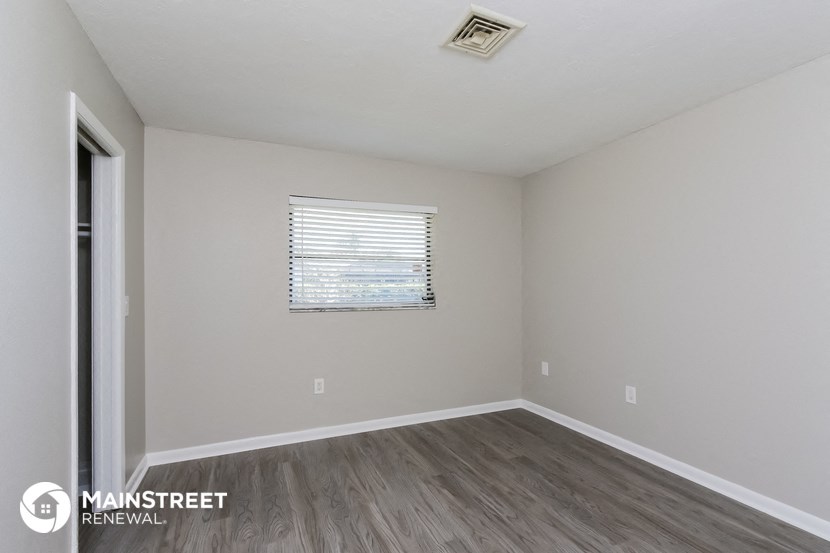 an empty room with wood flooring and a window
