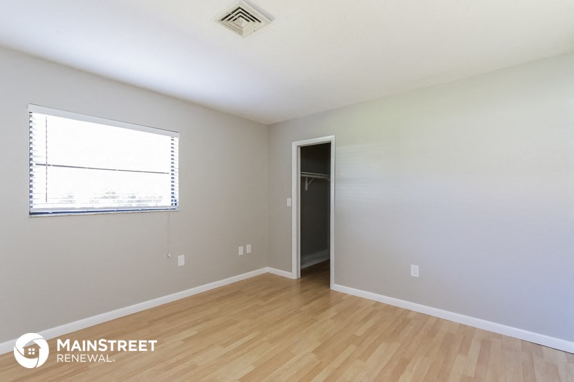 the living room of a home with wood flooring and a window