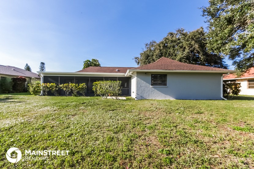a white house with a grassy yard and a tree