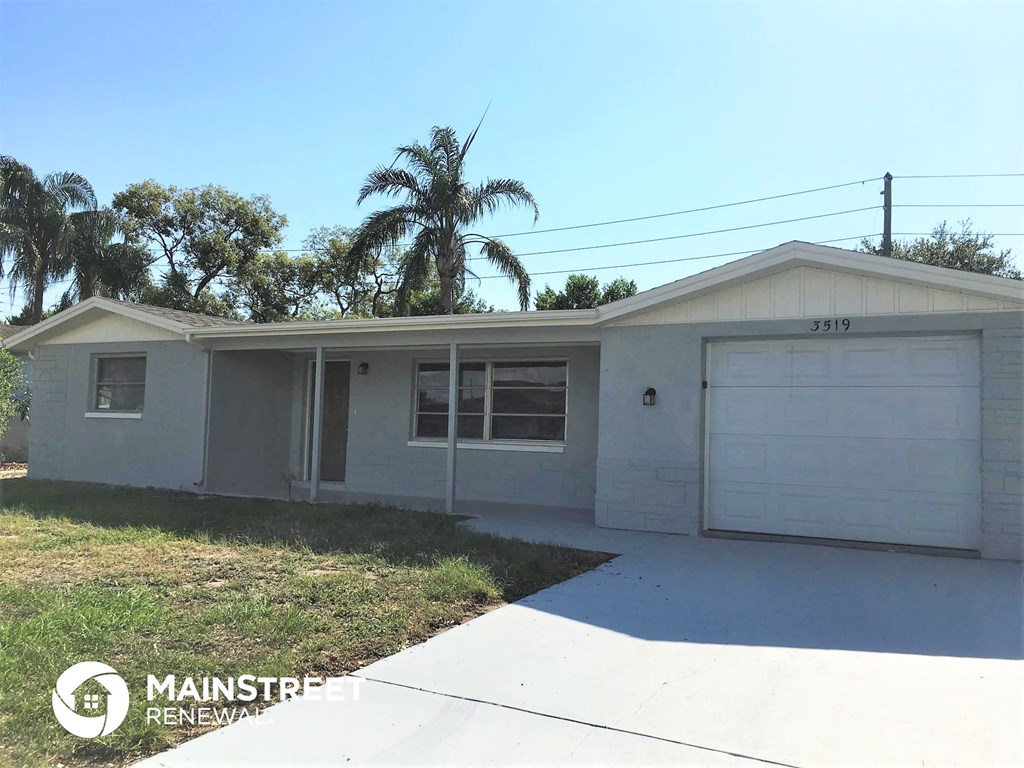 a small white house with a garage and palm trees