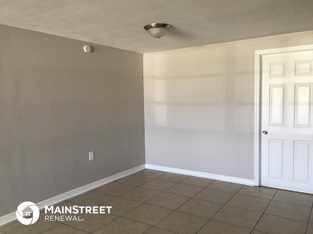 an empty room with a tile floor and a white door