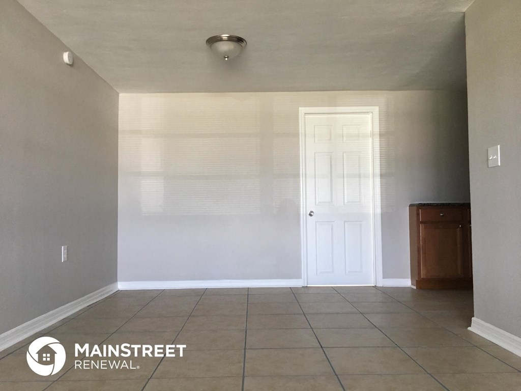 an empty living room with a tile floor and a white door