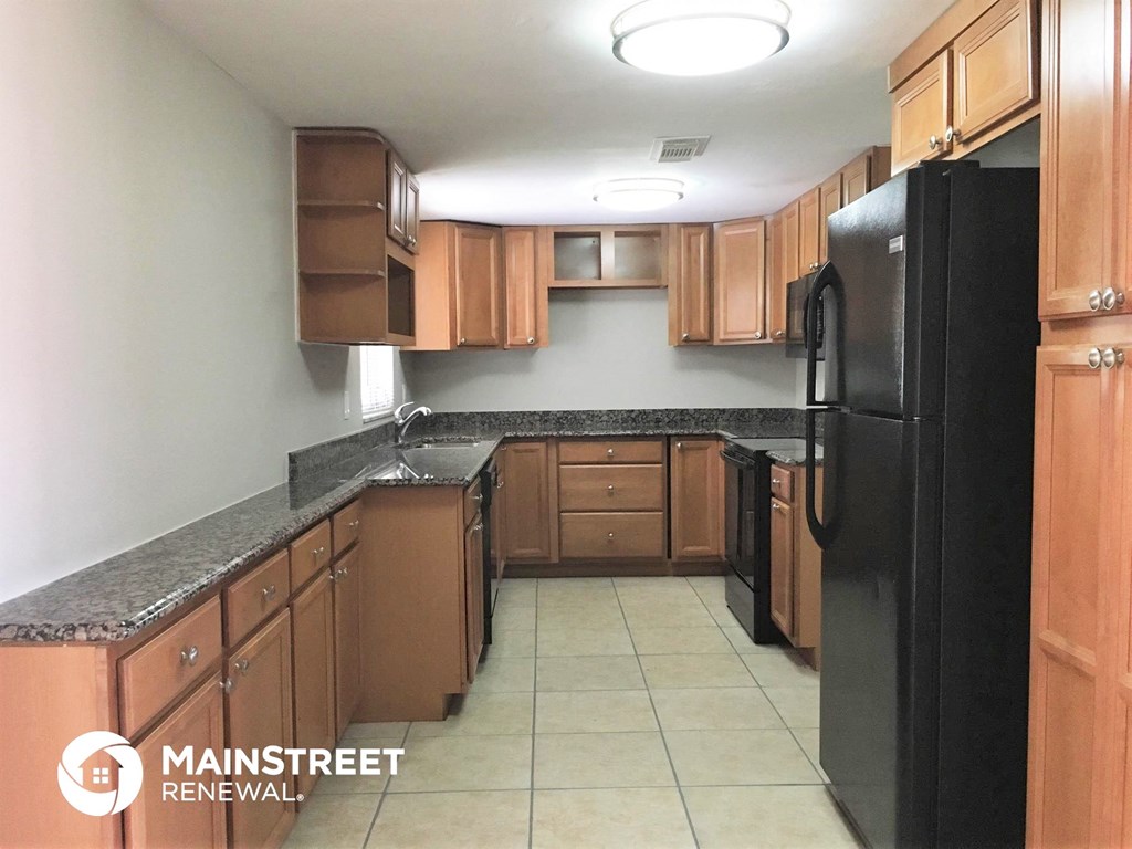 an empty kitchen with black appliances and wooden cabinets