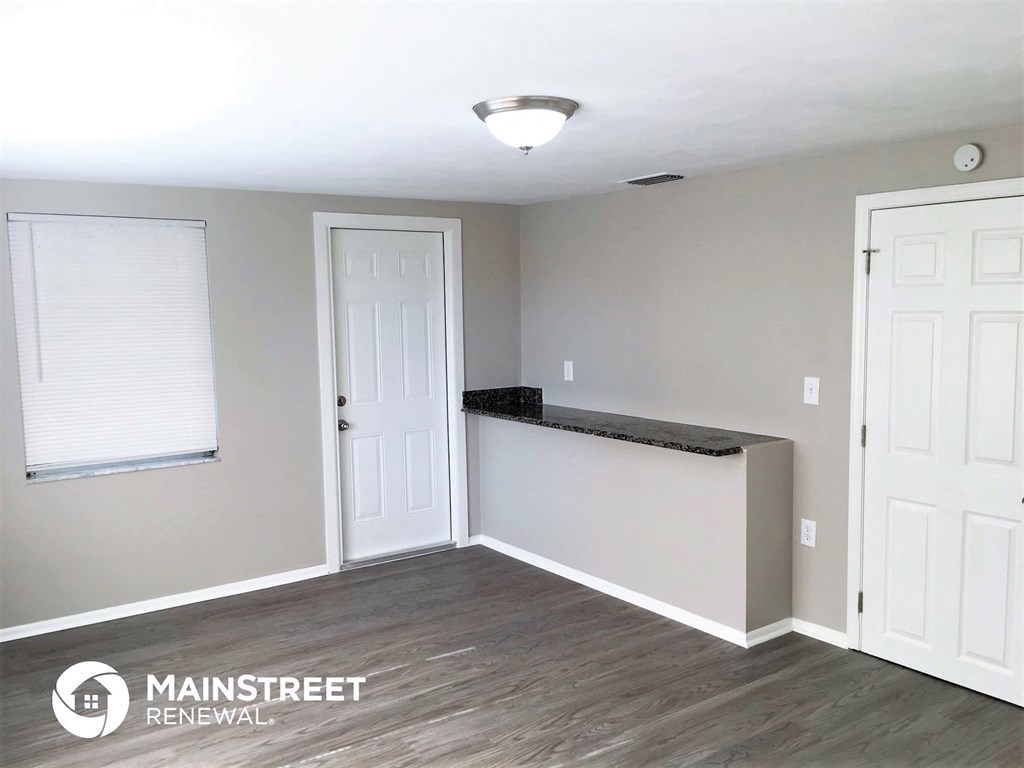 an empty living room with a counter and a white door