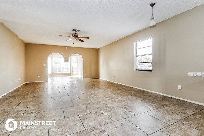 an empty living room with tile floors and a ceiling fan