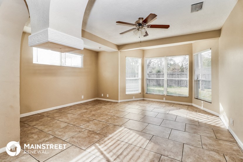 an empty living room with a ceiling fan and windows