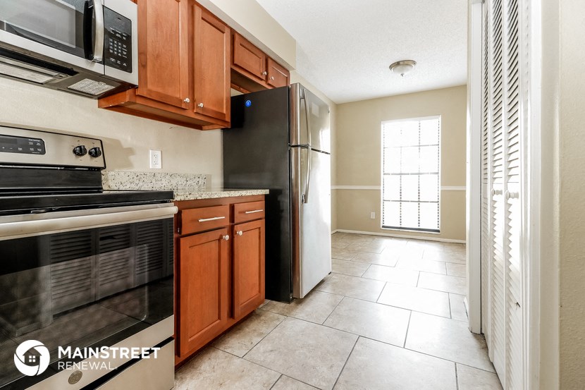 a kitchen with black appliances and wooden cabinets and tile floor