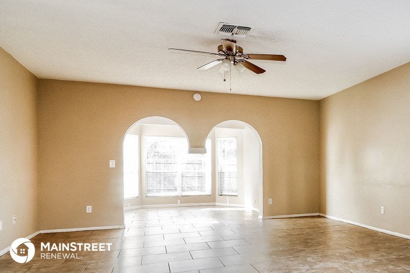 an empty living room with a ceiling fan and a large window