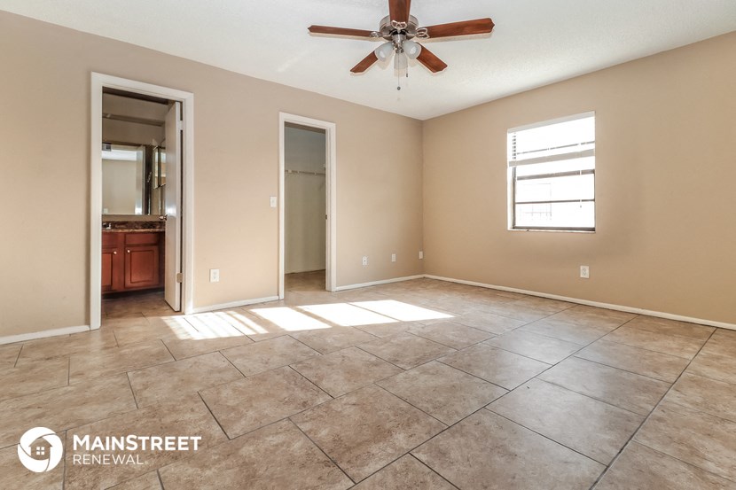 an empty living room with tile floors and a ceiling fan