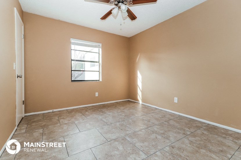 the spacious living room with tile flooring and a ceiling fan