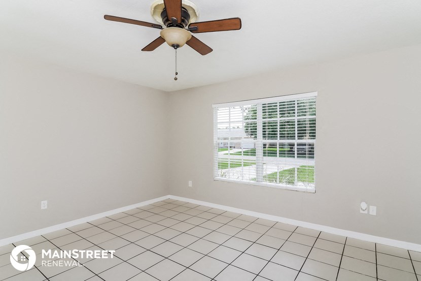 an empty living room with a ceiling fan and a window
