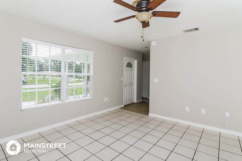 an empty living room with a ceiling fan and a large window
