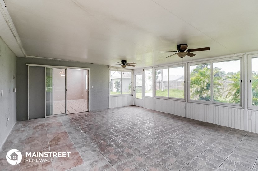 an empty living room with ceiling fans and large windows