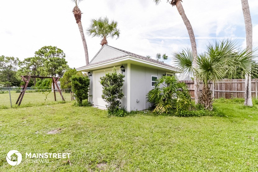 a small white house in a backyard with palm trees
