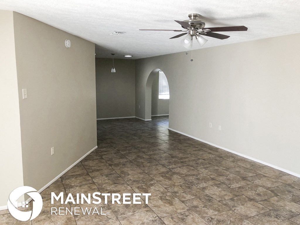 an empty living room with a ceiling fan and tile floor