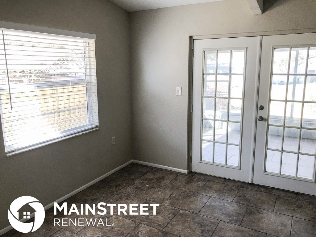 a small room with a door and windows and a tile floor