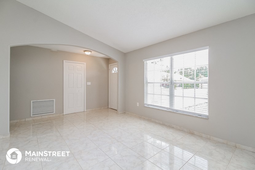 an empty living room with a large window and a white door