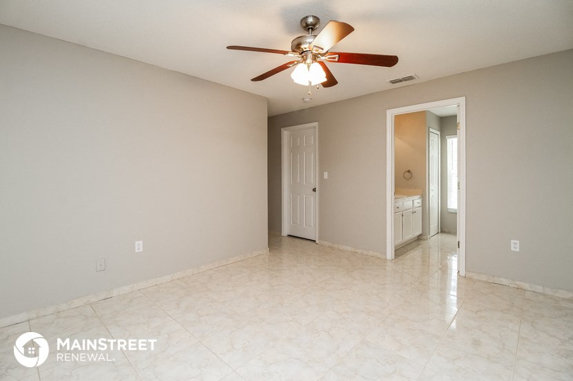 the spacious living room with ceiling fan and tile floor