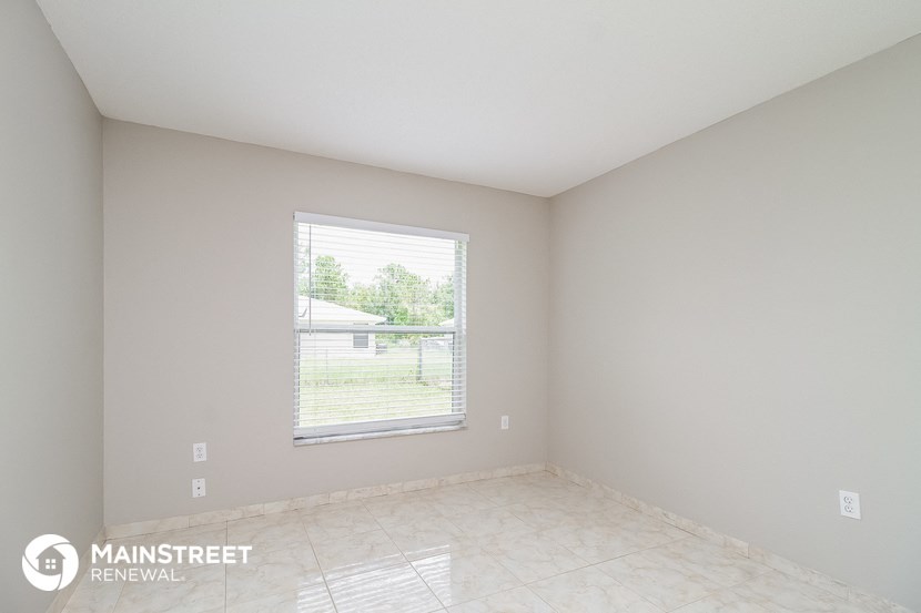 an empty room with a large window and a tiled floor