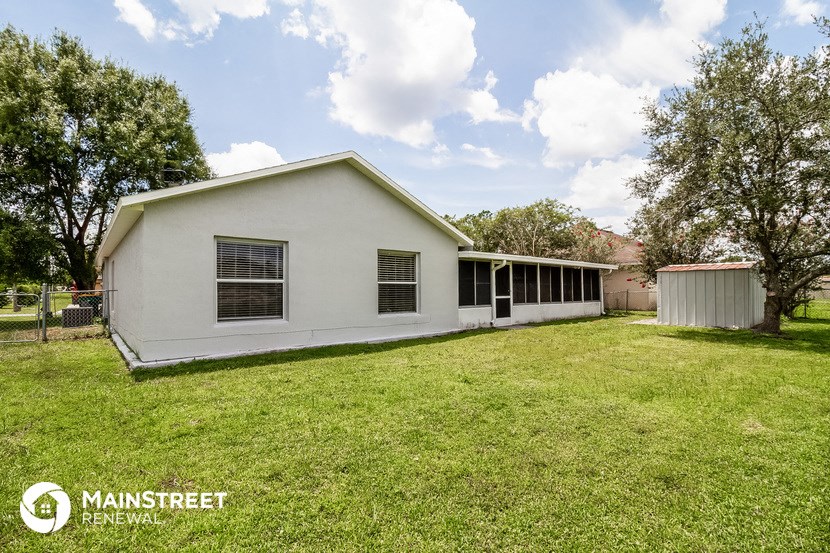 a white house with a grassy yard and a shed
