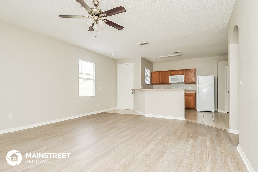 an empty living room and kitchen with a ceiling fan