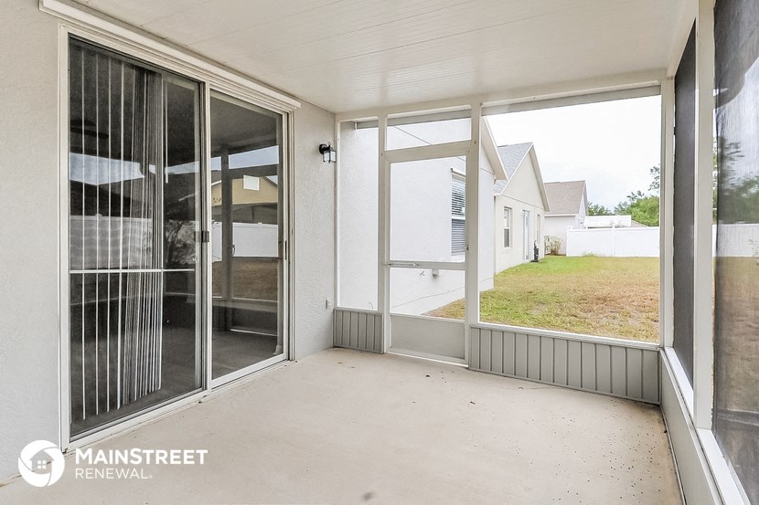 the view from the porch of a white house with glass doors and a patio