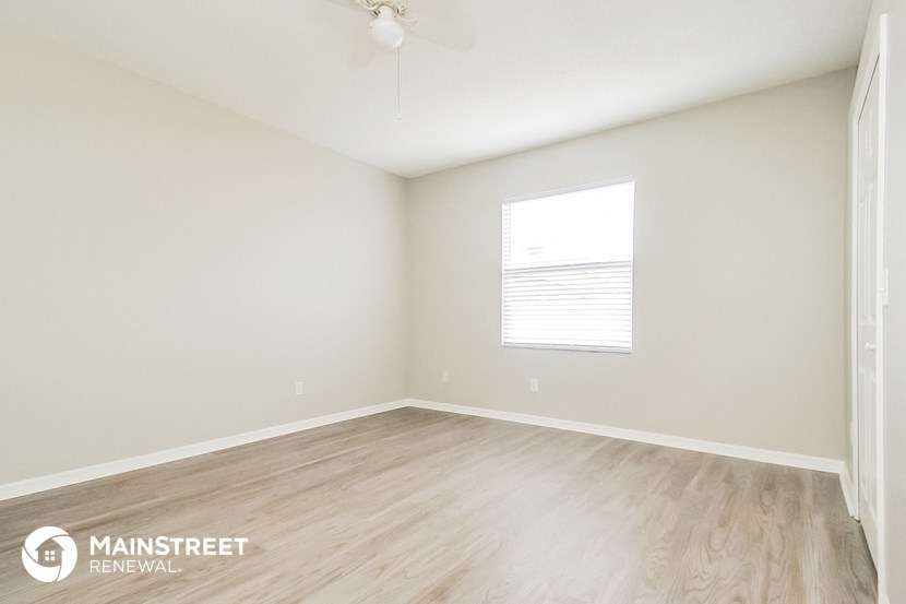 the spacious living room with wood flooring and white walls