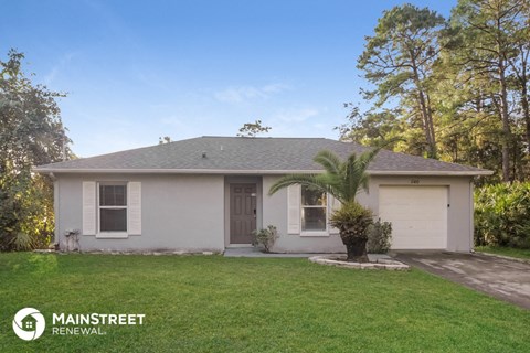 a small white house with a palm tree in the yard
