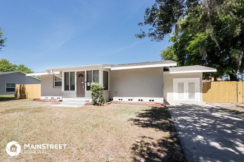 a small gray house with a yard and a white door